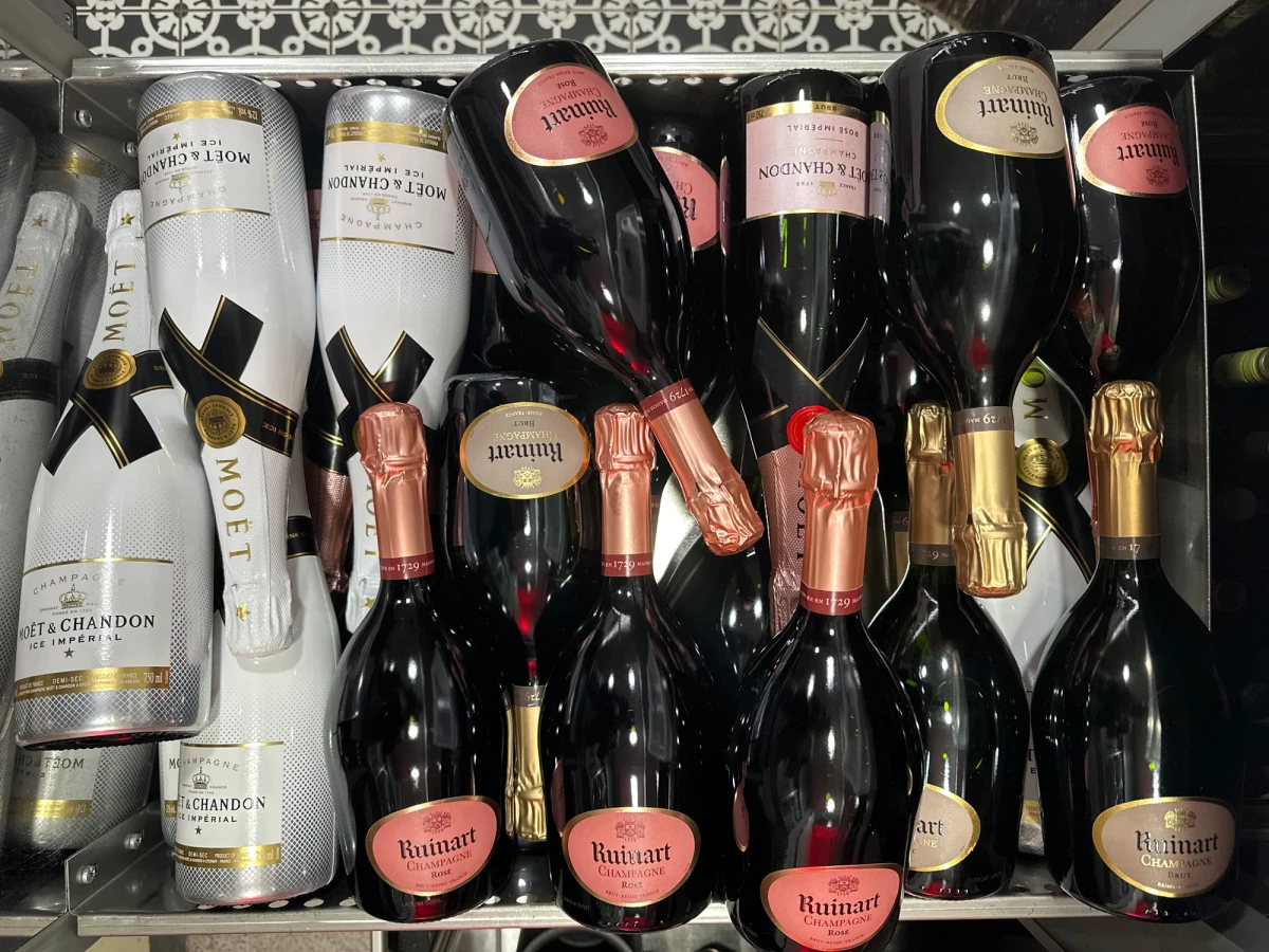 Sammlung von Champagner-Flaschen der Marke Mo&euml;t & Chandon und Ruinart in verschiedenen Gr&ouml;&szlig;en und Farbt&ouml;nen, dicht nebeneinander in einem Regal oder K&uuml;hlschrank angeordnet.