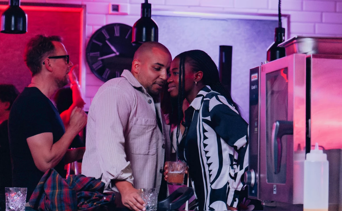 Junge Paare genießen Cocktails in stilvollem Eventküche-Ambiente.