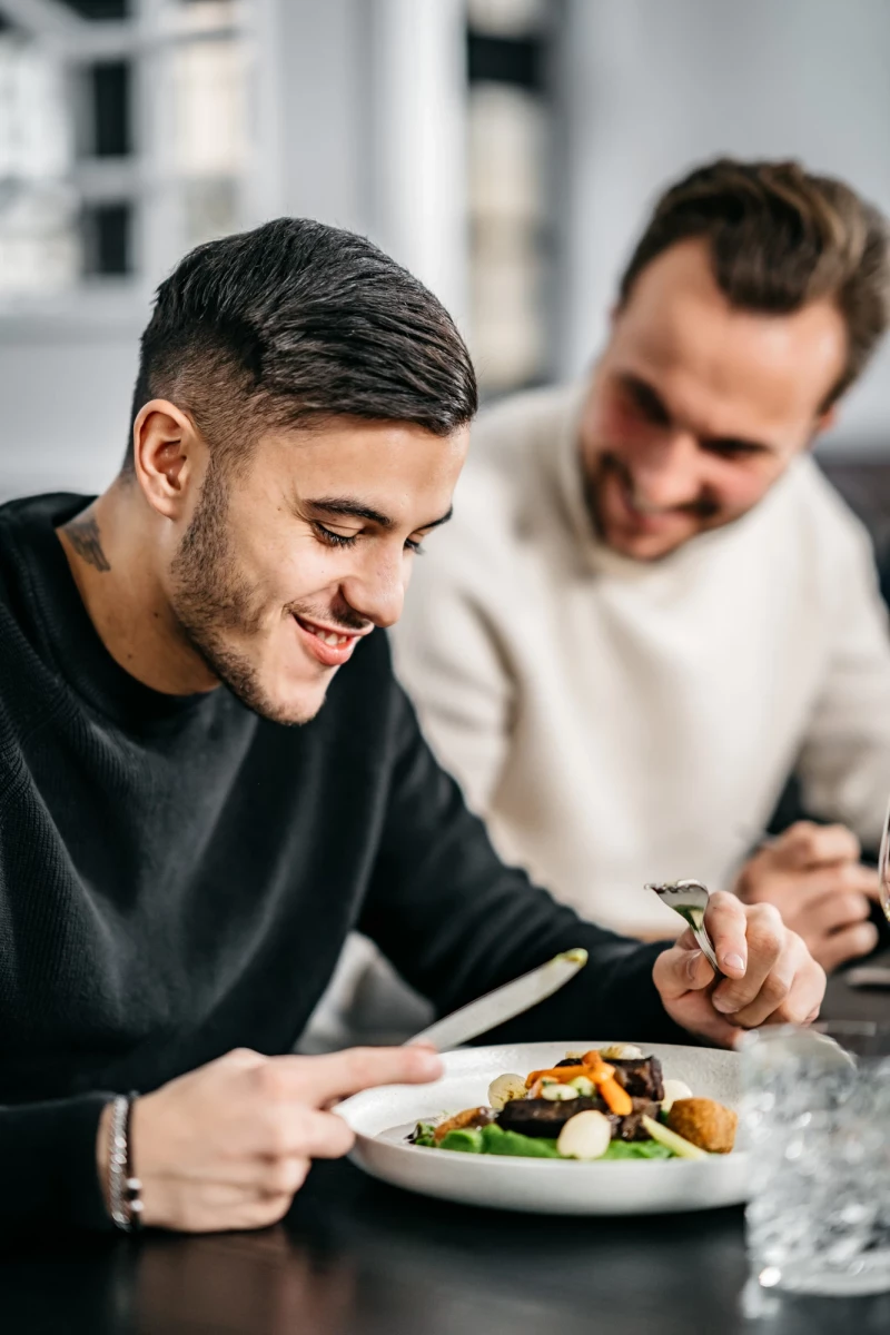 Zwei Männer genießen köstliches Essen im Hotel Riesengebirge.