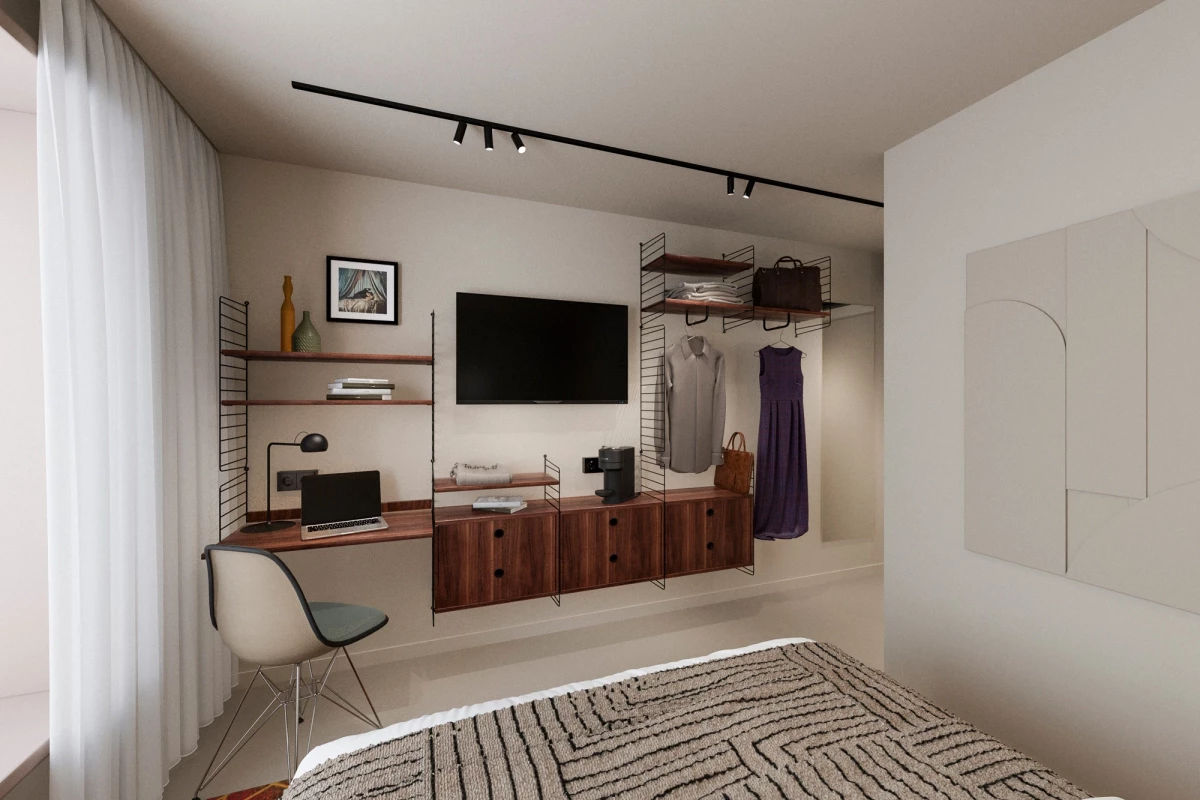 Modernes Hotelzimmer mit weißen Wänden, Holzmöbeln und minimalistischer Einrichtung. Ein schwarzer Fernseher hängt an der Wand, darunter ein Schreibtisch mit Laptop, daneben ein offenes Regal und eine Garderobe mit einer hängenden Jacke.